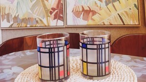 A table with two decorative glass candle holders on a woven placemat, set against a wall with abstract paintings. - Studio on Frioul Island: at the foot of a beach and the Morgiret calanque. (Marseille)