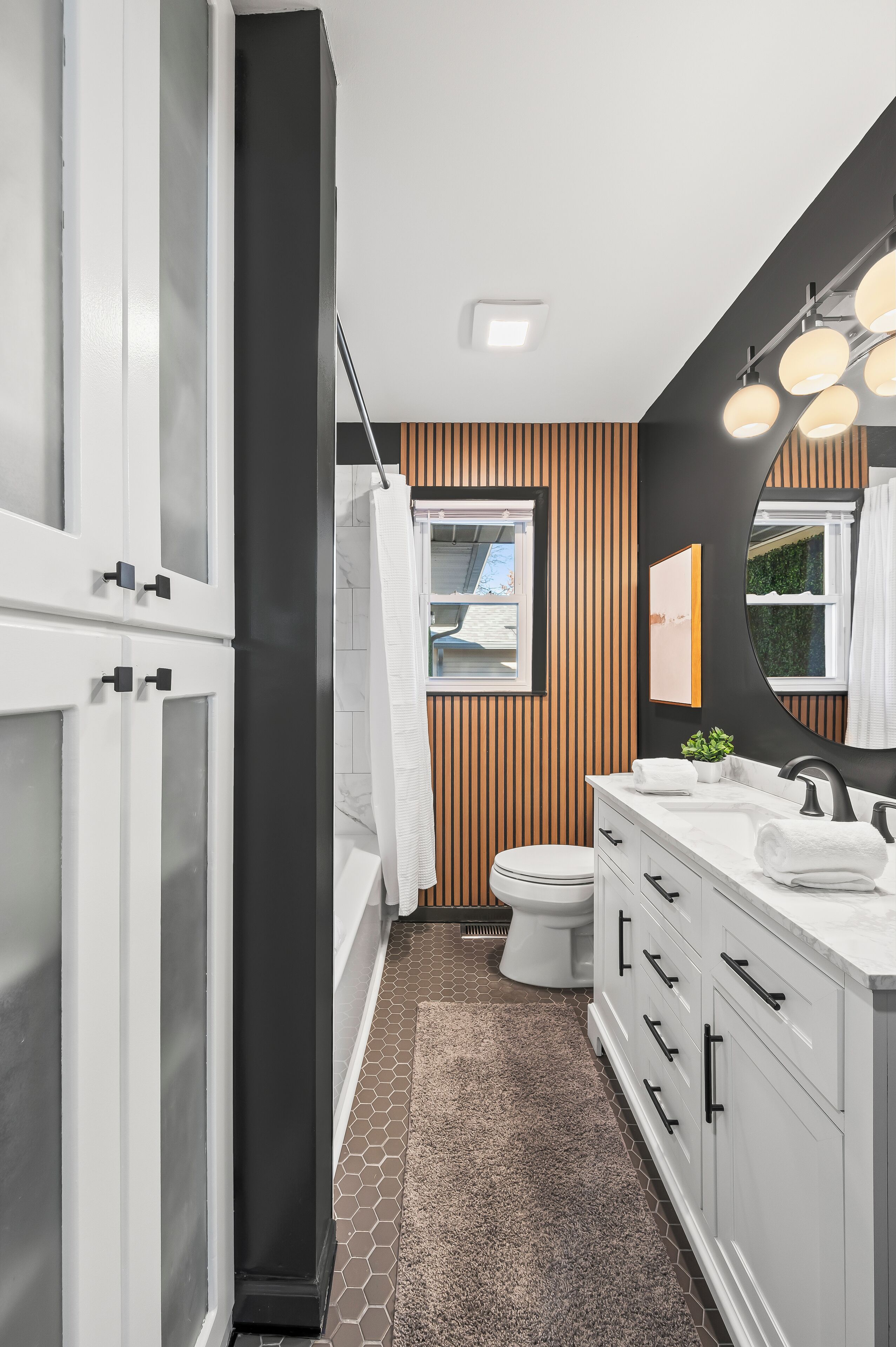 Une salle de bain moderne avec un meuble-lavabo blanc, un grand miroir et un espace douche.