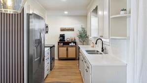A modern kitchen with a stainless steel refrigerator, wooden cabinets, a white countertop, and a built-in sink. - Relaxing Private Ranch Retreat–10 Mins to Downtown. Complete w/ your own Urinal! (Nashville)