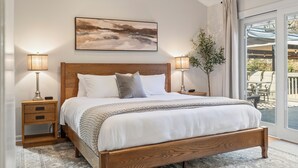 A bedroom with a wooden bed, two bedside tables with lamps, a large window with a view of the outdoors, and a painting on the wall. - Relaxing Private Ranch Retreat–10 Mins to Downtown. Complete w/ your own Urinal! (Nashville)