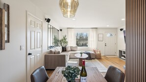 A modern living room with a dining table, a sofa, and a large window. - Relaxing Private Ranch Retreat–10 Mins to Downtown. Complete w/ your own Urinal! (Nashville)