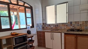 Eine Küche mit Holzausstattung, einer gefliesten Rückwand, einer eingebauten Mikrowelle und einem Fenster mit Blick ins Grüne.