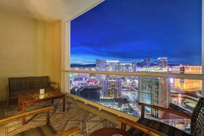 A balcony with a city view, a wooden table, and a sofa. - MGM Signature 35th Floor Jacuzzi Penthouse XL Balcony Strip View No Resort Fee (Las Vegas)