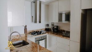 A modern kitchen with white cabinets, stainless steel appliances, and granite countertops. - Luxurious & Modern Apartment 1503 Building h2 (Cartagena de Indias)