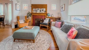 Un salon avec une cheminée, un canapé, une table basse et un tapis à motifs.
