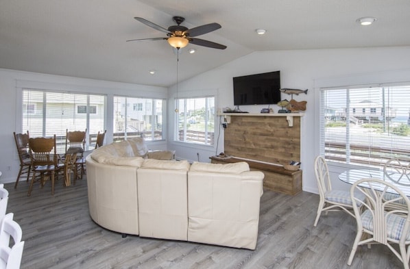 A spacious living room with a large beige sectional sofa, a dining area with wicker chairs, and a ceiling fan. - Reverie - Located in lovely, quiet Dune Allen Beach (Santa Rosa Beach)