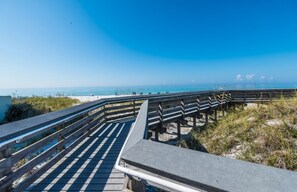 A wooden boardwalk leading to a beach with a clear blue sky.