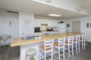 A modern kitchen with white cabinetry, a wooden island, and bar stools.