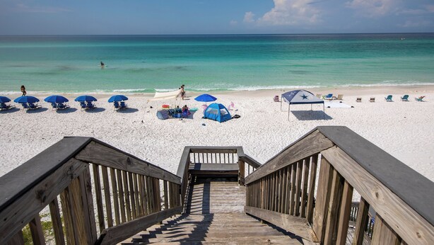 A wooden staircase leading to a beach with white sand, blue umbrellas, and beach chairs. - Blue Mountain Condos #22 (Santa Rosa Beach)