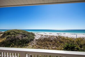 A beach with a clear view of the ocean and a white railing in the foreground.