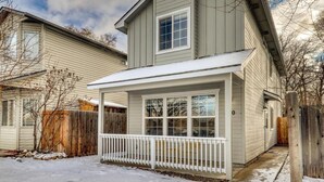 A two-story house with a covered porch and a fenced yard.
