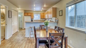 A spacious kitchen with wooden cabinets, a central island, and a dining area with a table and chairs.