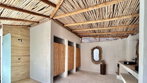 A spa room with a wooden floor, a thatched ceiling, and a stone wall. - Sunset hills Apartments  (Mazatlán)