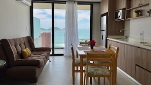 A modern kitchen with a dining area, a sofa, and a view of the sea. - Sunset hills Apartments  (Mazatlán)
