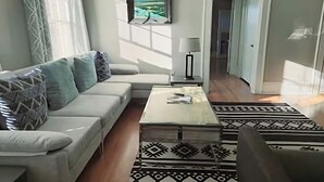 A living room with a sofa, a coffee table, a patterned rug, and a painting on the wall. - The Park Overlook (Charlotte)