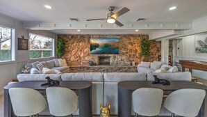 A modern living room with a stone accent wall, a fireplace, a large window, and a ceiling fan.