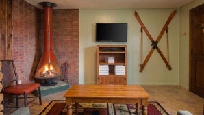 A cozy room with a fireplace, a television, and a wooden shelf with towels. - "A" Antelope Cabin - South Fork (South Fork)