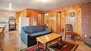 A compact living space with a kitchenette, a sofa, a wooden dining table, and a chair. - "A" Antelope Cabin - South Fork (South Fork)