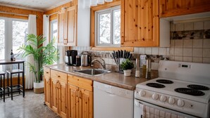 Une cuisine avec des meubles de rangement en bois, un évier, une cuisinière et une machine à café.