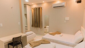Habitación de hotel con escritorio, dos camas, una silla, un espejo y una cortina.