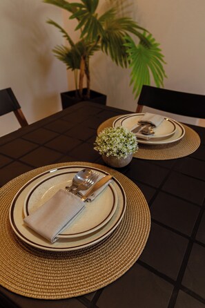 A dining table set with plates, cutlery, and a small potted plant. - LOFT Bragança Suite Hotel (Bragança)