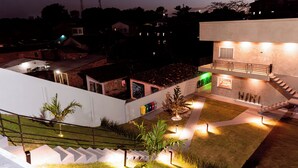 Un edificio moderno con una escalera, un pequeño jardín con plantas y una pared exterior blanca.