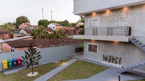 Un edificio moderno con techo plano, una escalera y un pequeño árbol en el patio.