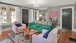 A living room with a green sofa, pink armchairs, and a chandelier.