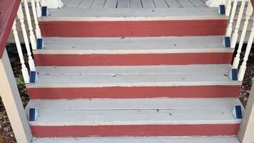 A wooden staircase with red and white steps leading to a dark door.