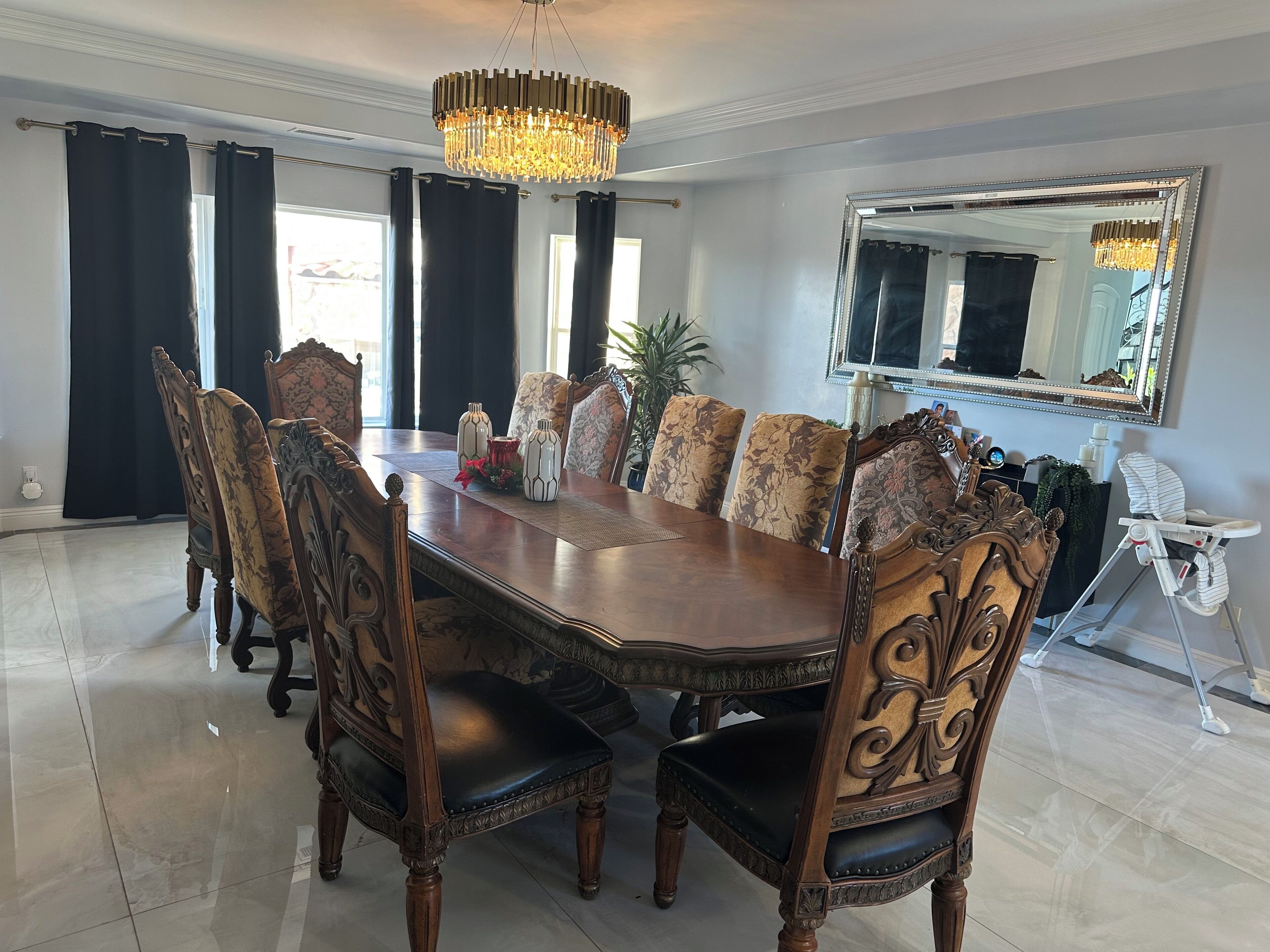 A formal dining room with a large wooden table, ornate chairs, and a chandelier.