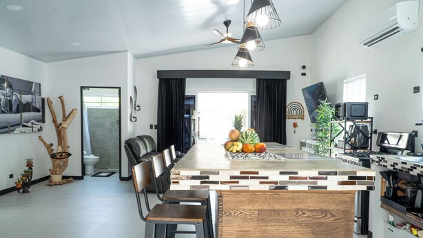 A modern kitchen with a central island, bar stools, and a dining area with a long table.