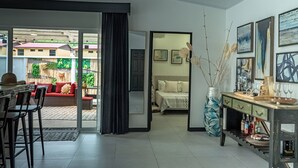 A modern living room with a sofa, dining area, and a bed. There is a large window with a view of the outside.