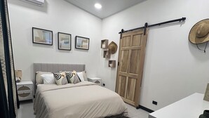 A modern bedroom with a bed, a white dresser, a fan, and a sliding door.