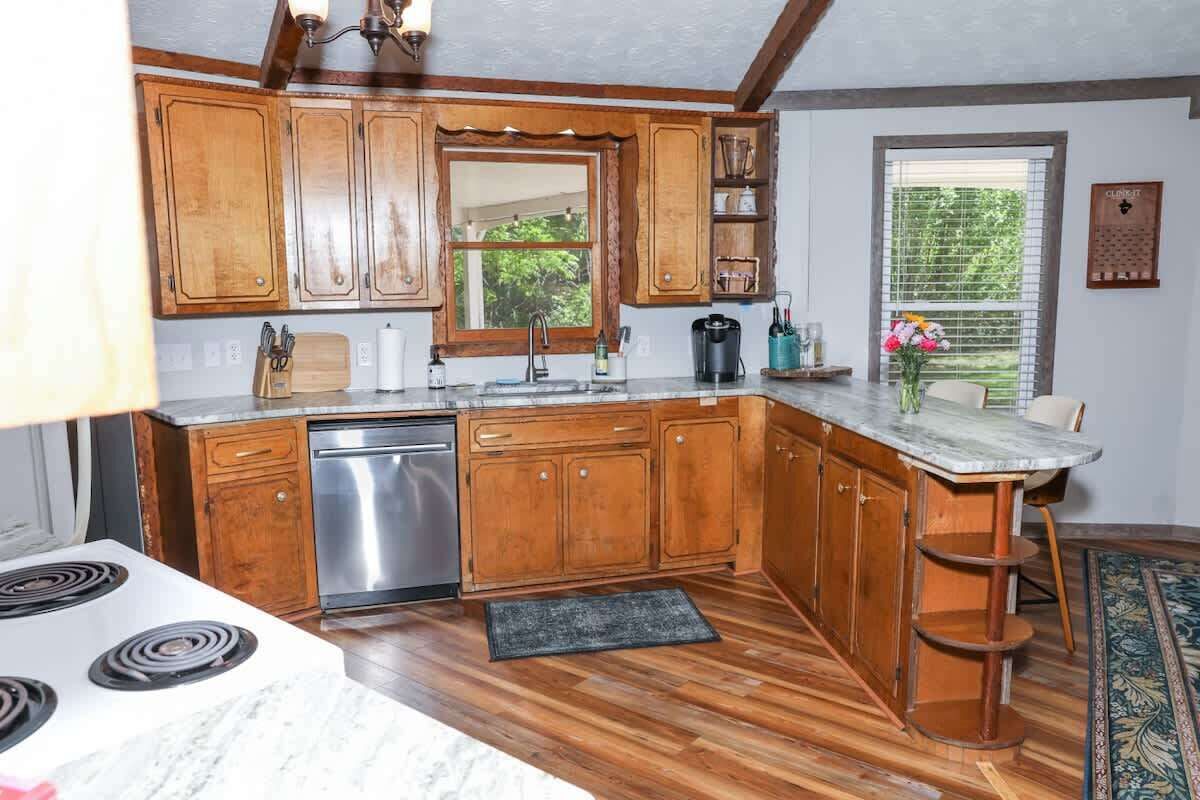 A kitchen with wooden cabinets, a stainless steel dishwasher, and a marble countertop.
