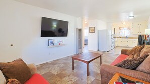 A living room with a flat-screen TV, a wooden coffee table, and a sofa.