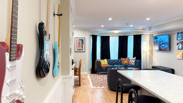 A modern living room with a sofa, a dining table, and a kitchen area.