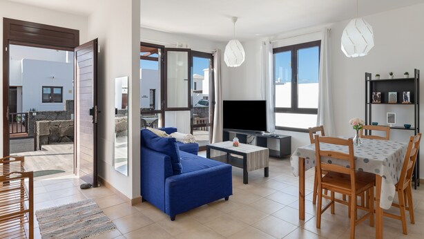 A modern living room with a sofa, TV, dining table, and chairs. - Vacation Villa 'Luxury  Lanzarote' with Sea View, Private Pool and Wi-Fi (Playa Blanca)