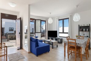 Un salon moderne comprenant un canapé, un téléviseur, une table à manger et des chaises.