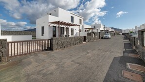 A residential street with white houses, stone walls, and a clear sky. - Vacation Villa 'Luxury  Lanzarote' with Sea View, Private Pool and Wi-Fi (Playa Blanca)