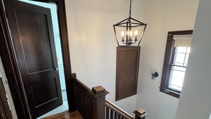 A wooden staircase with a dark finish, a hanging light fixture, and a window with a white blind. - Warm, charming 3BR house w fenced yard in quiet neighborhood close to everything (Springfield)