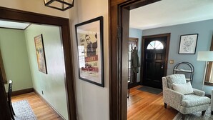 A hallway with wooden flooring, a hanging light fixture, framed pictures on the walls, and a door leading to another room. - Warm, charming 3BR house w fenced yard in quiet neighborhood close to everything (Springfield)