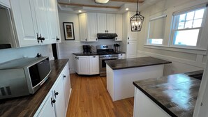 A modern kitchen with white cabinets, a central island, and a built-in microwave. - Warm, charming 3BR house w fenced yard in quiet neighborhood close to everything (Springfield)