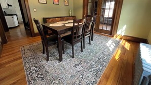 A dining area with a wooden table, chairs, a patterned rug, and a chandelier. - Warm, charming 3BR house w fenced yard in quiet neighborhood close to everything (Springfield)