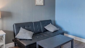A modern living room with a dark leather sofa, two matching cushions, and a small table. - Ocean View Condo Sleeps 4! (Myrtle Beach)
