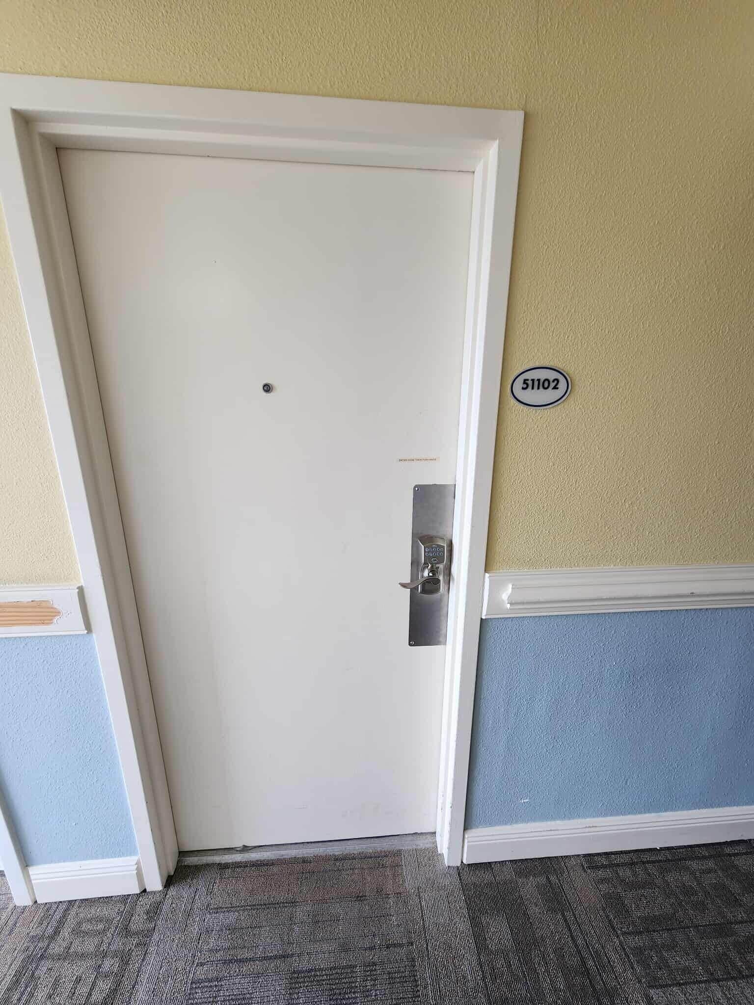 A closed door with a lock, a number plate '51102' on the wall, and a carpeted floor.