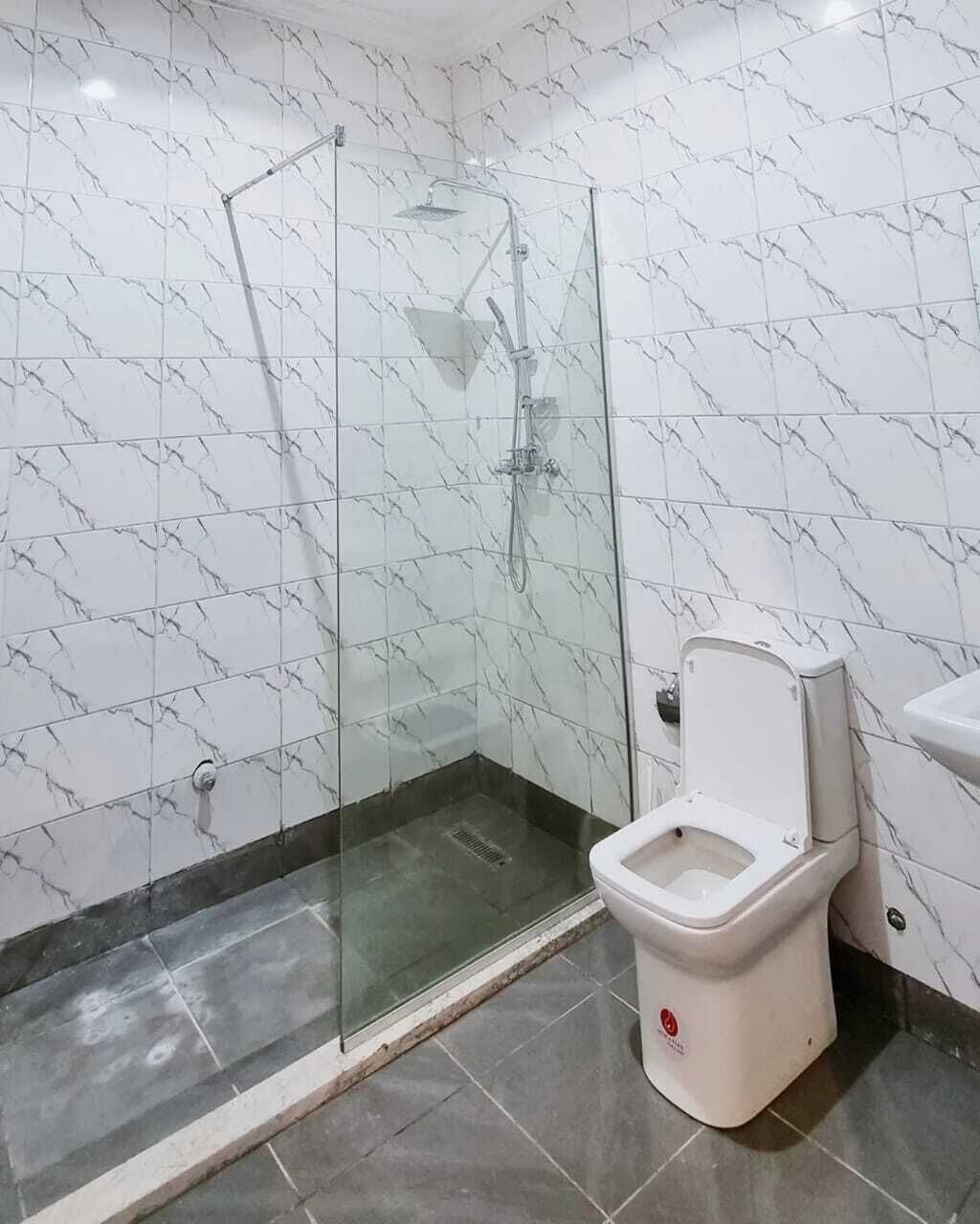 A bathroom with a glass-enclosed shower, a toilet, and a sink.