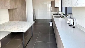 A modern kitchen with marble countertops, a built-in oven, and a sink. - Boya Apartments (Abuja)