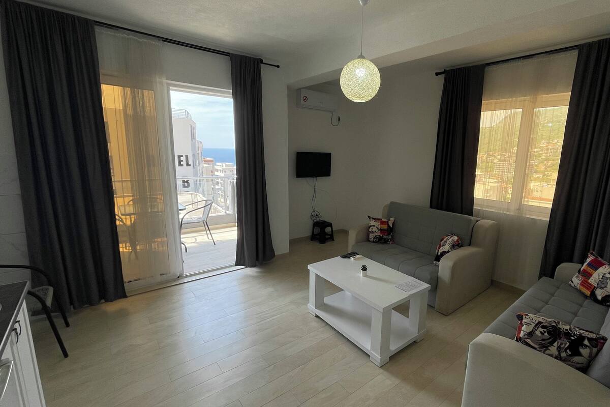 A modern living room with a sofa, a coffee table, and a TV mounted on the wall.