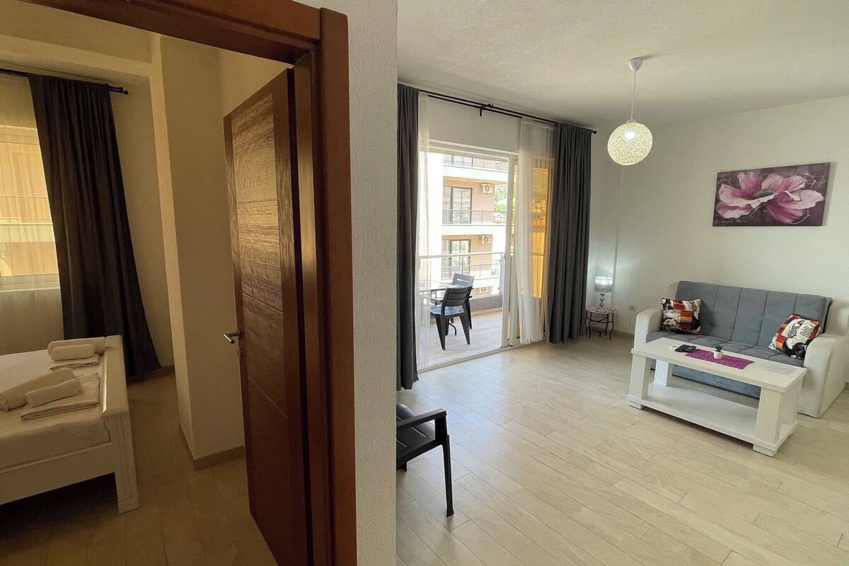 A living room with a sofa, a coffee table, and a dining area with a table and chairs.