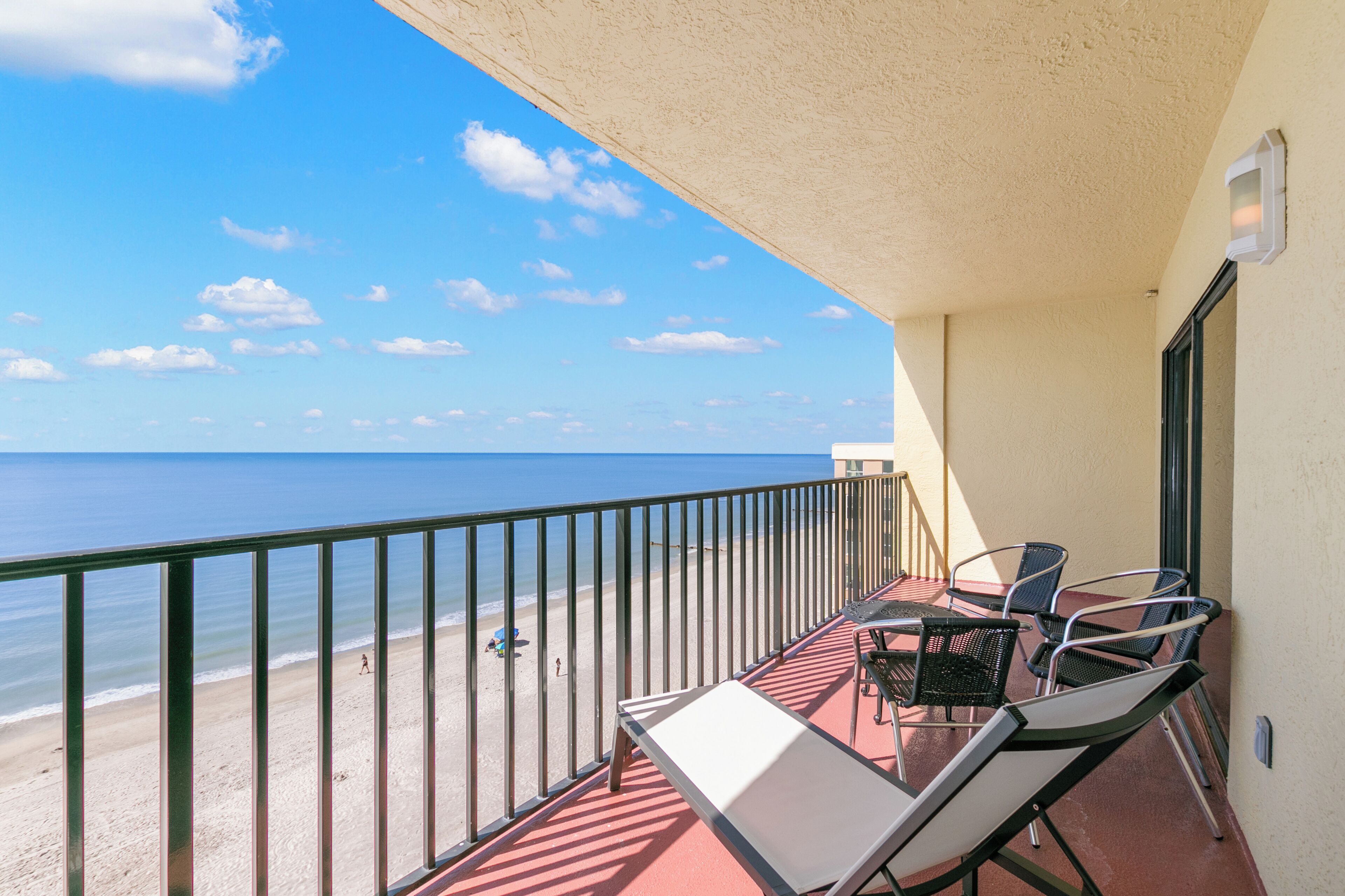 A balcony with a view of the beach and ocean.
